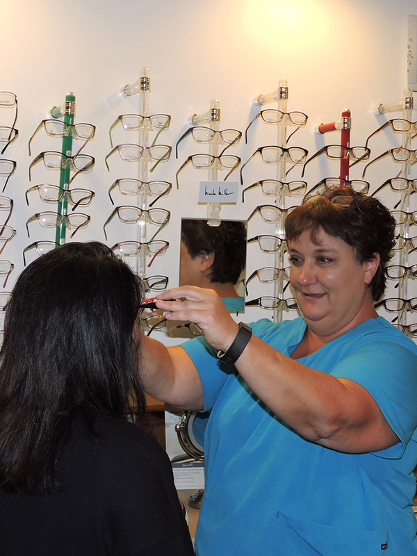 photo of lucy simmons placing a pair of glasses on a client