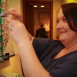 photo of employee at kull family eye care grabbing a pair of eyeglasses off a display wall