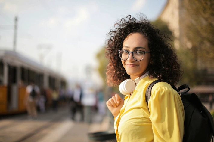 photo of a woman outside a trolley station wearing glasses in front of a blurry background